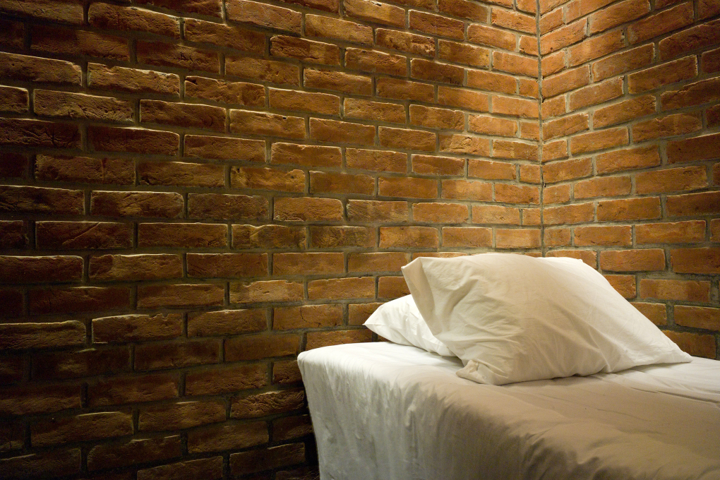 The spare simple interior of a dormitory with exposed brick. (Photo: Eric Chenal)