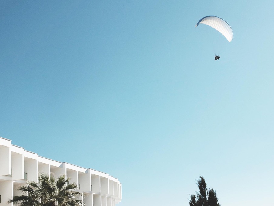 Suspended in surreality, a parachutist hovers above the curved white cellular hotel structure. (Photo: Gili Merin)