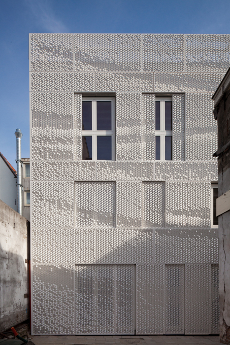 White perforated metal panels with a graphic pattern cover the fa&ccedil;ade and also double as sliding shutters in front of the windows and doors. &nbsp;(Photo: I See For You / F&ouml;llmi Photography)