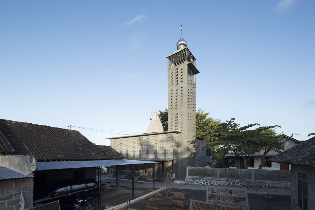 The overall form of the mosque is a striking contrast to surrounding buildings. The soaring boxy tower appears to dominate the landscape of dusty roads and the greyish roof tiles of villagers&rsquo; houses.