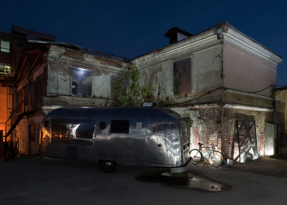Contrasting textures of old building fabric, shiny pipe-insulation foil cladding and silver airstream caravan.