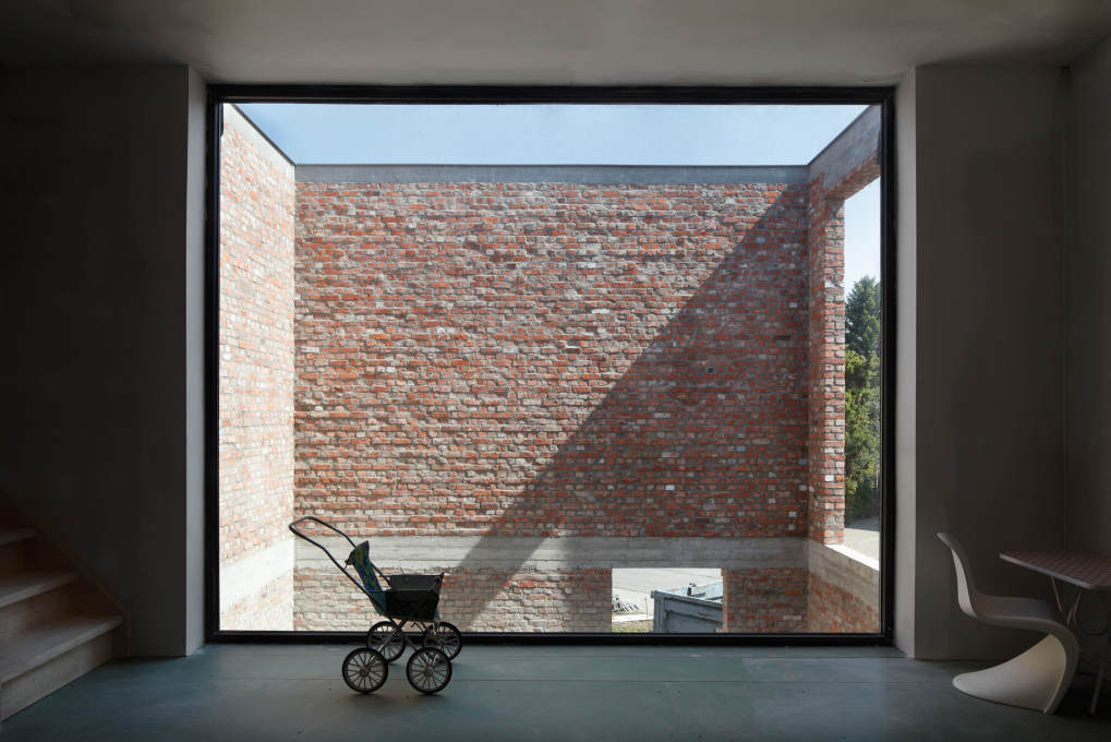 On completion, the two-storey high patio brings daylight into the heart of the house, visually making the raw brick walls a integral background element in the interior.