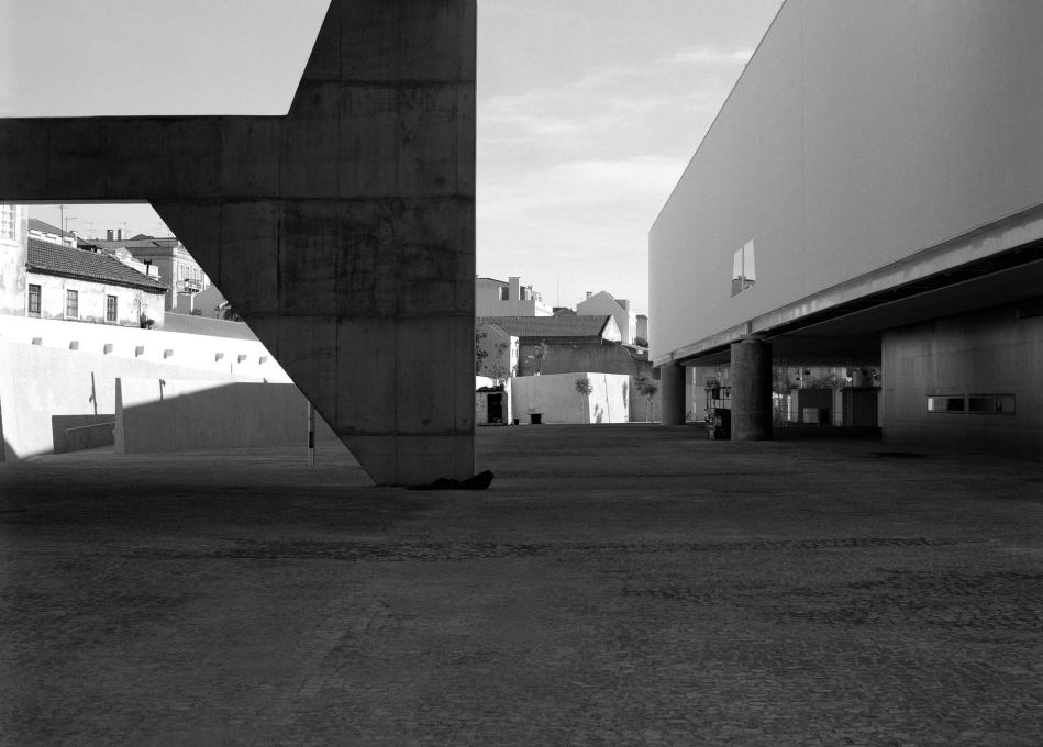 View of the public square; the concrete structure supporting part of the &ldquo;annex&rdquo; building (left) and the volume for the exhibitions with the glazed entrance and maintenance workshop on the ground floor (right) (Photo: Nuno Cera).