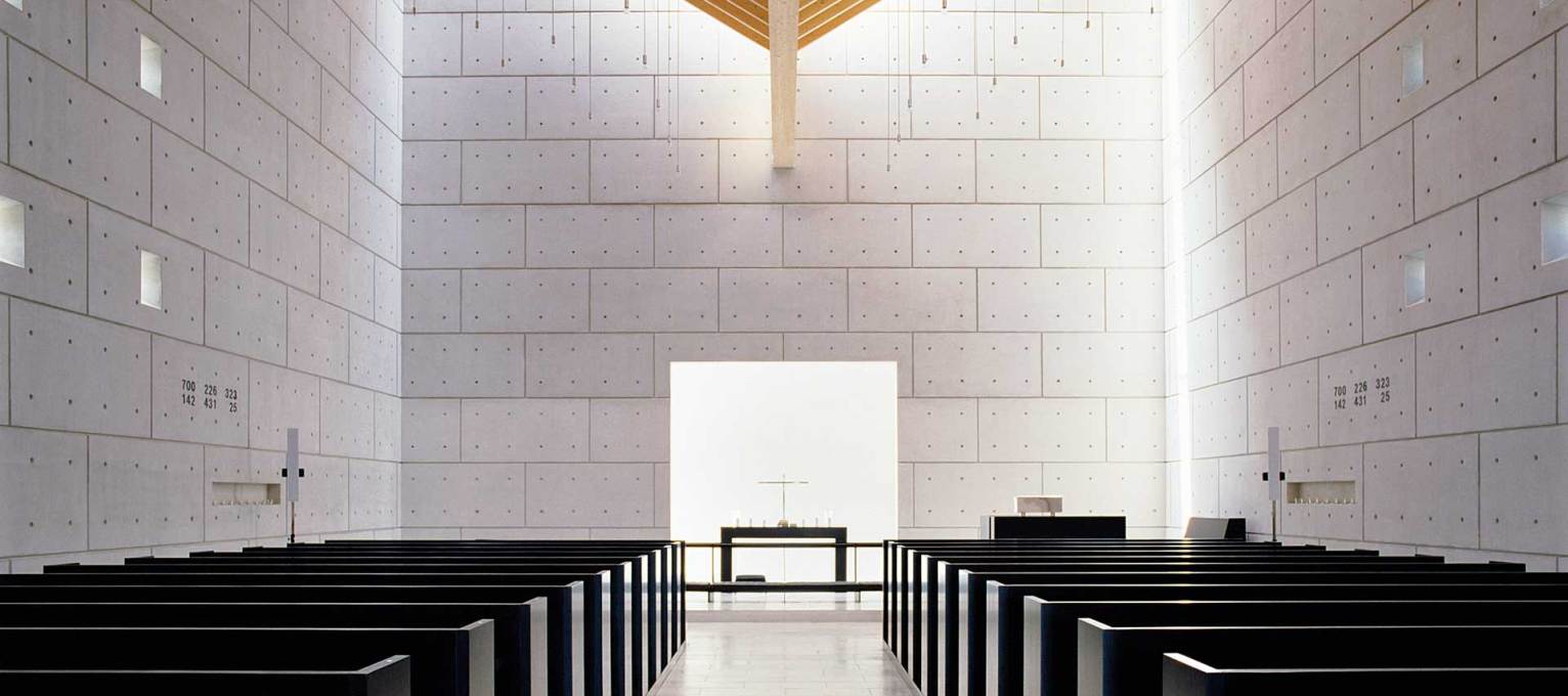 The interior of Enghoej Church, Denmark (1994), showing the black-stained wood pews, contrasting with the in-situ concrete walls, its whiteness coming from the addition of marble aggregate (Photo courtesy Henning Larsen Architects)