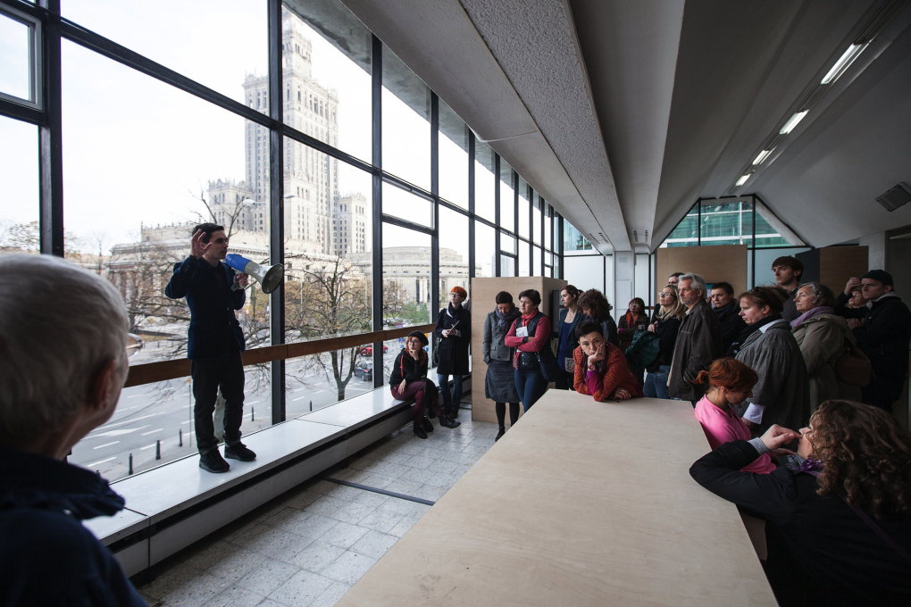 Guided tour by MoMA curator Tomasz Fudala explaining the architecture of the Emilia pavilion with the Parade Square and the Palace of Culture and Science in the background. (Photo: Bartosz Stawiarski, 2012)