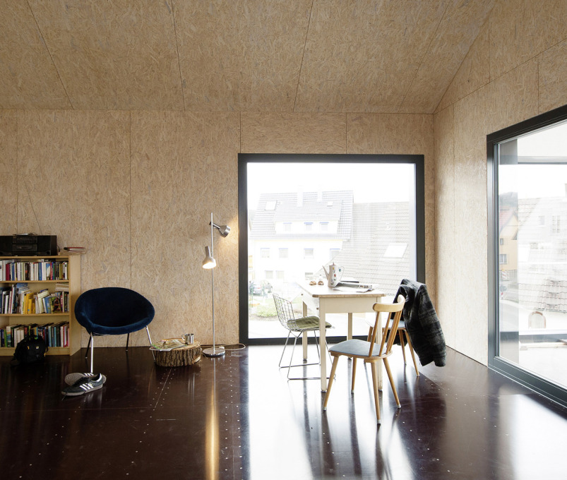 Large windows ensure the upstairs&rsquo; interior is well lit. Inexpensive materials dominate: coarse chipboard panels, varnished white for the walls, and a floor of cladding boards. (Photo: Sebastian Berger)